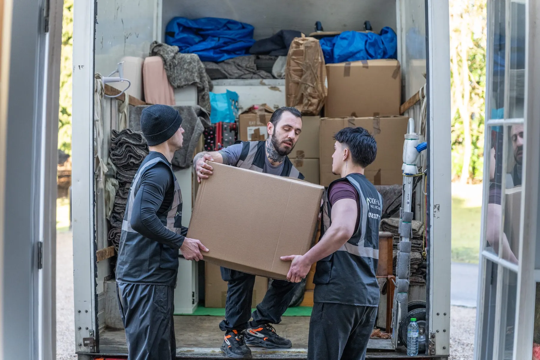 Two Cookham Removals & Storage crew members carrying a large box from the house to the Luton van