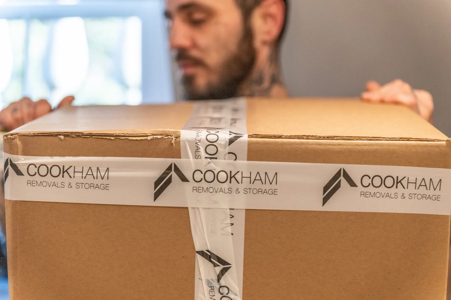 A cardboard box sealed with Cookham Removals & Storage branded tape