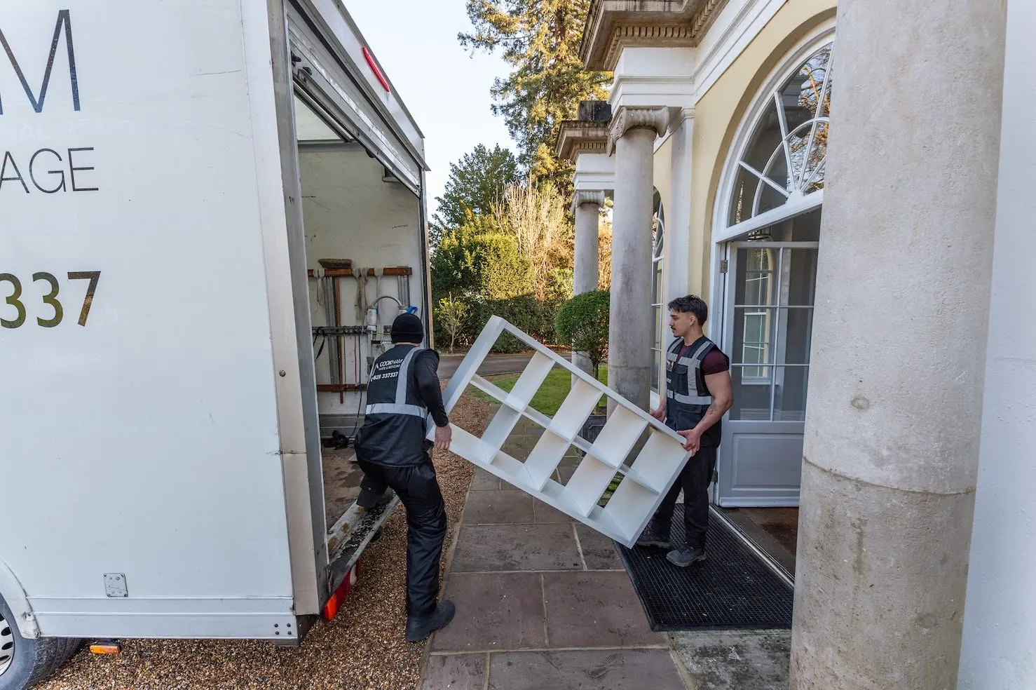 Two Cookham Removals & Storage crew members guiding a large framed item down the van ramp