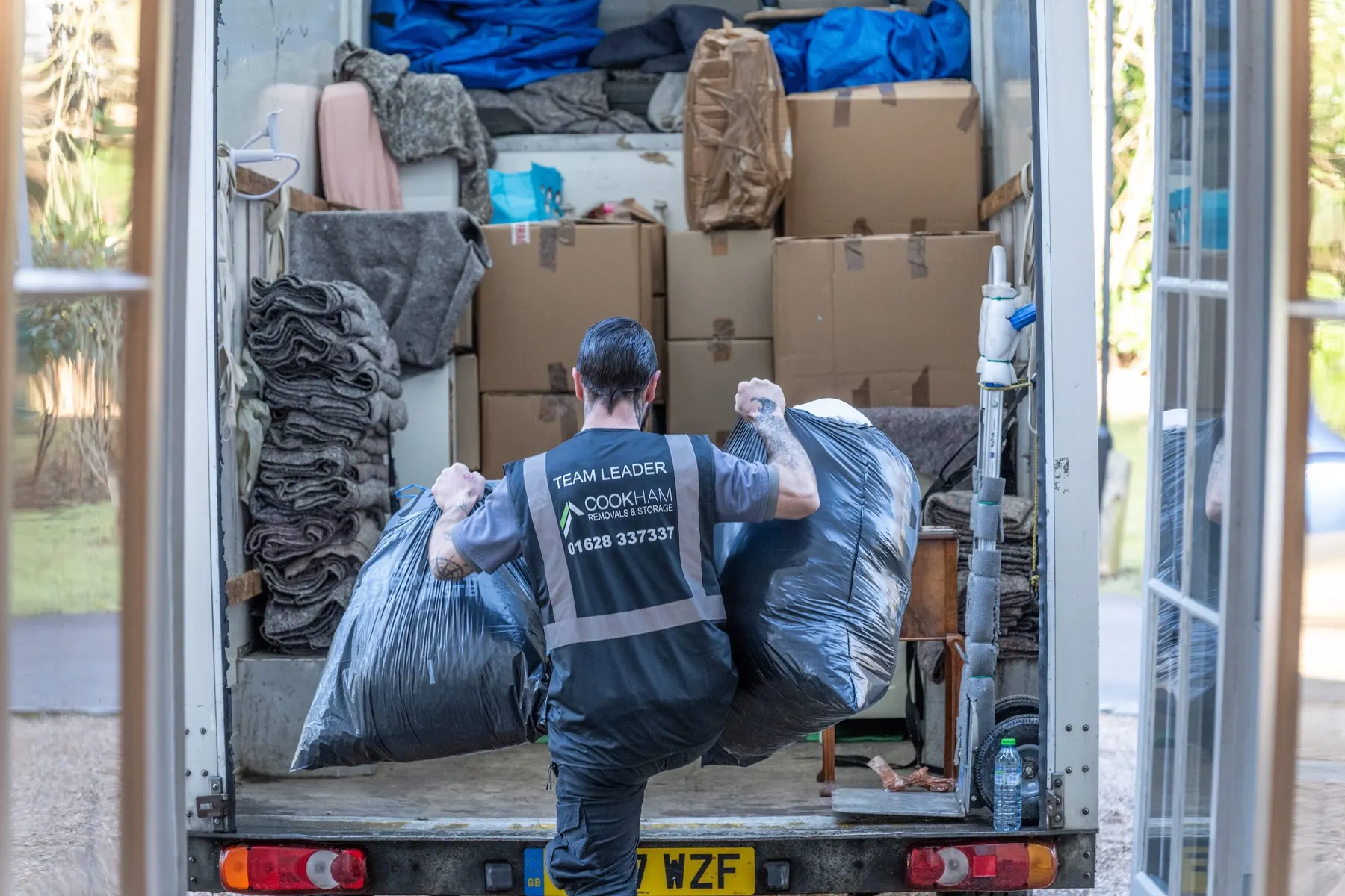 A Cookham Removals & Storage crew member lifting bagged items into the Luton van