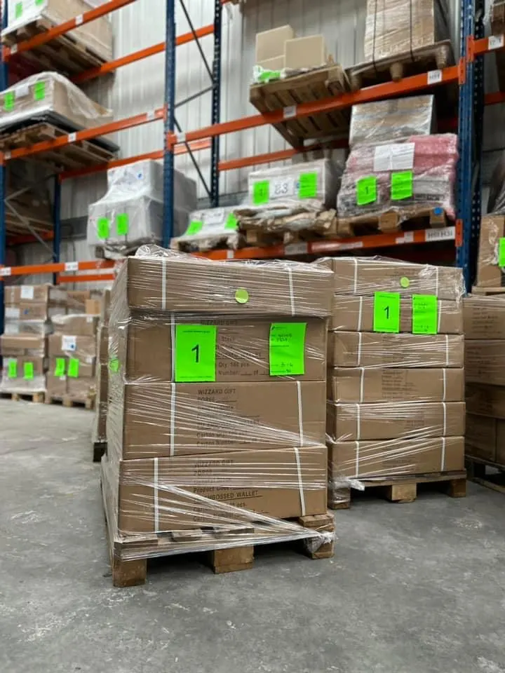 Shrink-wrapped pallets with green labels standing on the warehouse floor
