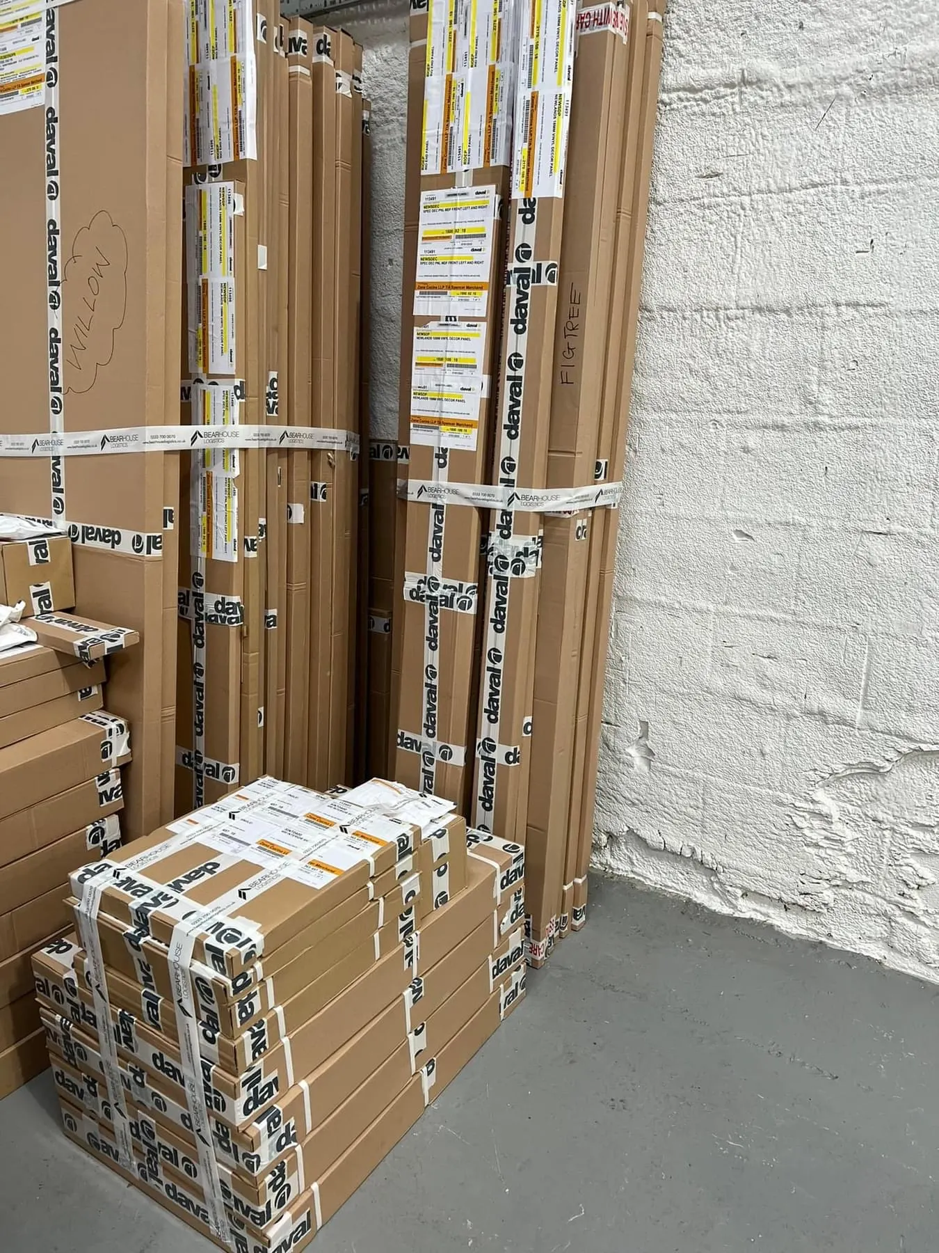 Boxes strapped together and stacked against a white wall in the storage warehouse
